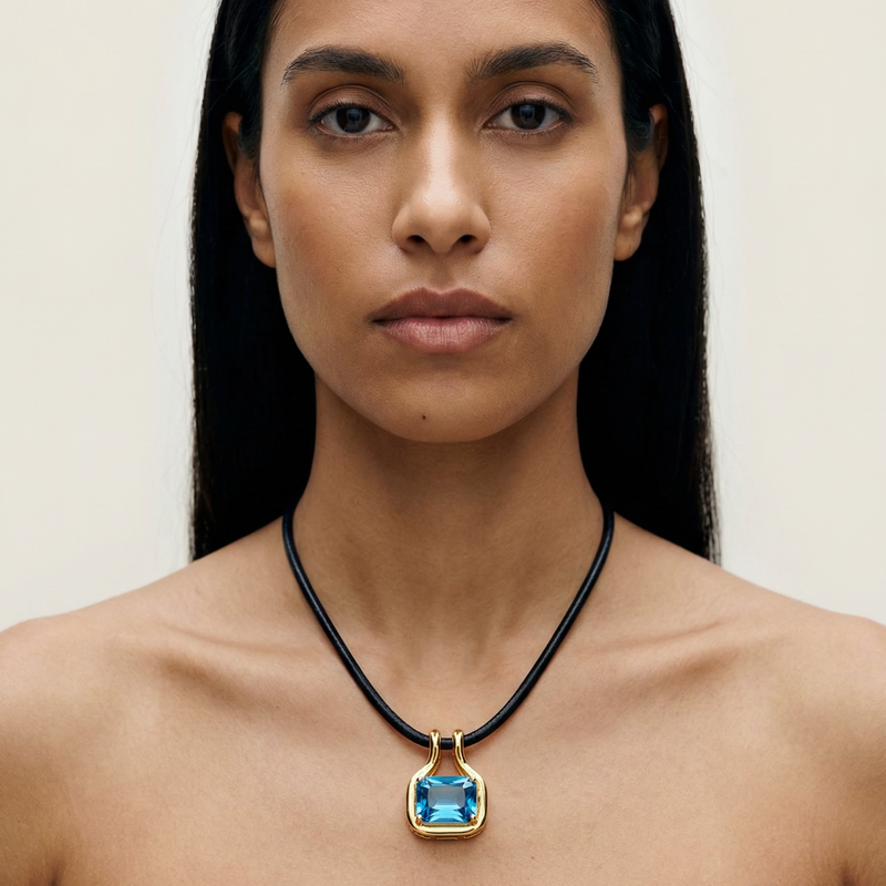 Woman wearing a necklace with a blue pendant against a neutral background