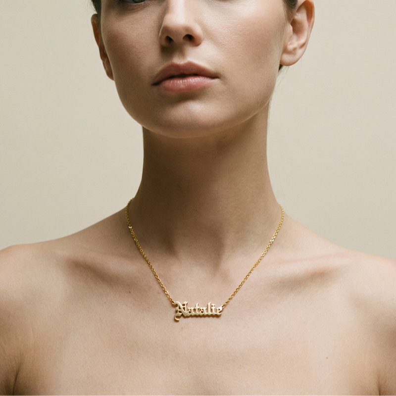 Woman wearing a gold necklace with 'Natalie' on a neutral background